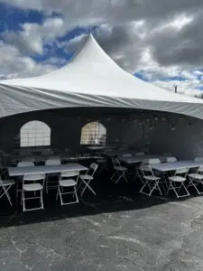 a white tent with tables and chairs in a parking lot