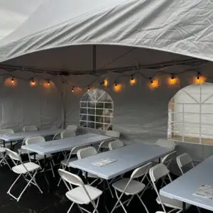 Cozy tent rentals for outdoor events featuring tables, chairs, and warm string lighting for perfect ambiance.