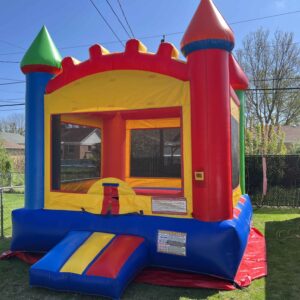 Colorful inflatable bounce castle with red, yellow, blue, and green towers set up on a sunny backyard lawn.