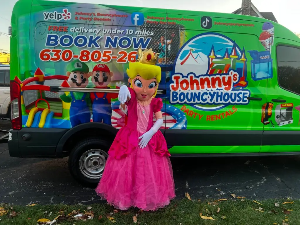 a pink princess mascot dressed in a pink dress in front of the johnny party rentals van