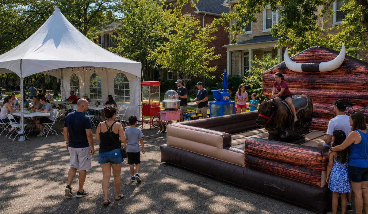 Chicago block party with a mechanical bull, event tent, tables, chairs, concessions, and families enjoying party equipment rentals in Chicago.
